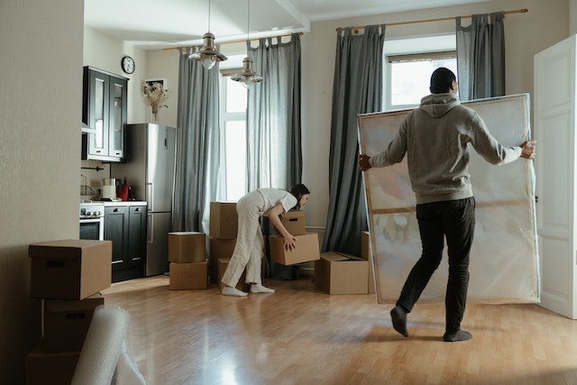 two people moving boxes into a home